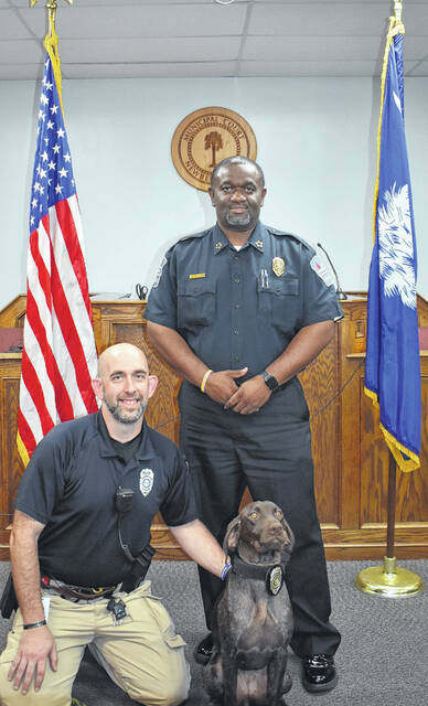 K-9 Officer Kira with her handler Sgt. Wilbur Bouknight (kneeling) and Chief Kevin Goodman (standing).
                                 Courtesy photo